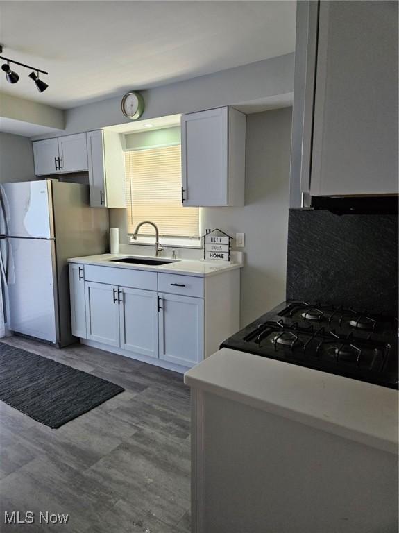 21731 Nicholas Ave, Euclid, OH 44123 - kitchen featuring freestanding refrigerator, white cabinetry, light countertops, wood finished floors, and backsplash
