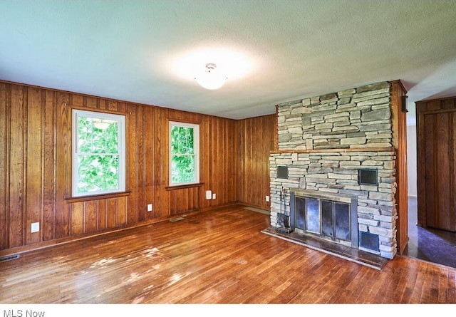 3371 Brecksville Rd, Richfield, OH 44286 - unfurnished living room with a fireplace, hardwood / wood-style floors, wooden walls, and a textured ceiling