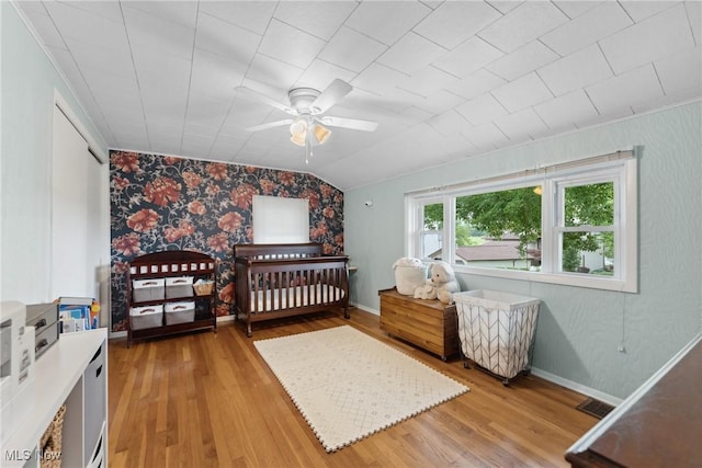 4324 Ormond Dr, New Franklin, OH 44319 - bedroom featuring light wood finished floors, wallpapered walls, lofted ceiling, an accent wall, and a nursery area