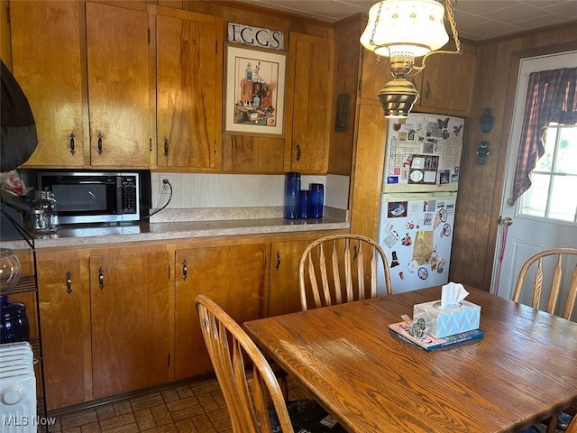 330 E Main St, East Palestine, OH 44413 - kitchen with freestanding refrigerator, stainless steel microwave, brown cabinetry, brick patterned flooring, and light countertops