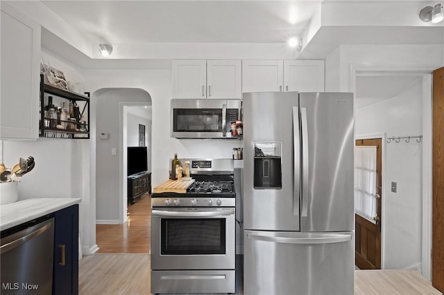 5910 Gerald Ave, Parma, OH 44129 - kitchen with stainless steel appliances, white cabinets, arched walkways, light wood-style floors, and light countertops