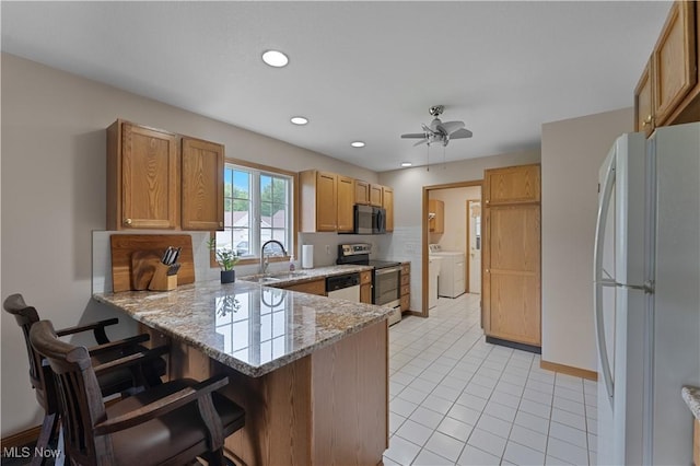 7876 Walnut St Unit B, Boardman, OH 44512 - kitchen featuring stainless steel appliances, washer and dryer, a peninsula, backsplash, and a breakfast bar
