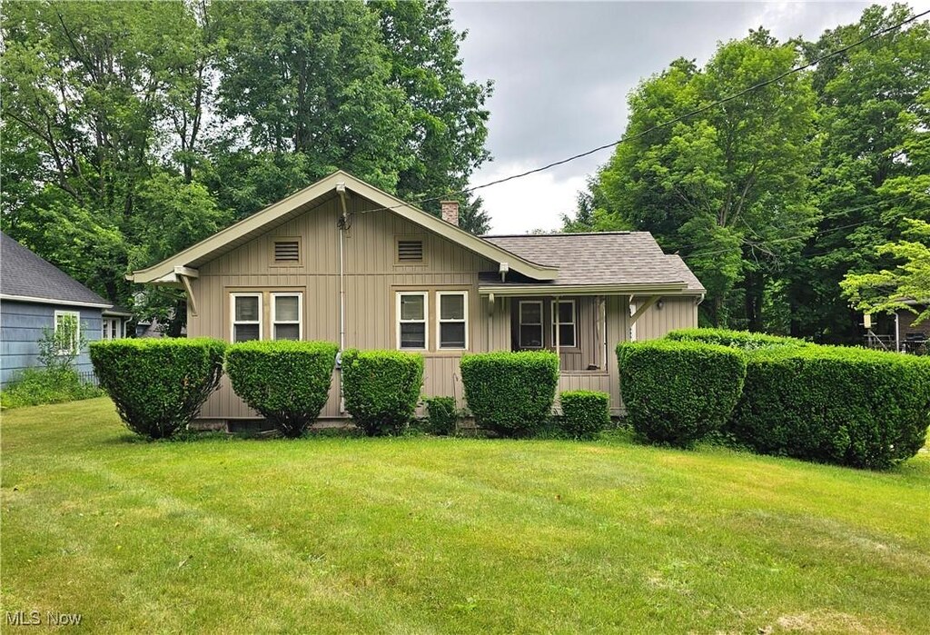 168 Munroe Falls Ave, Munroe Falls, OH 44262 - view of front of house with board and batten siding, a front lawn, a chimney, and roof with shingles