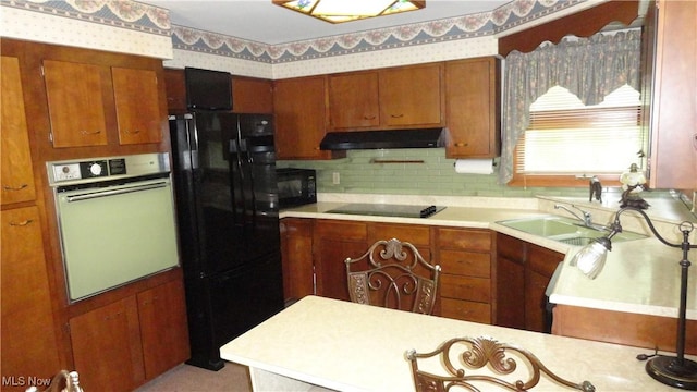 3981 Washington School Rd, New Cumberland, WV 26047 - kitchen featuring black appliances, under cabinet range hood, light countertops, brown cabinetry, and wallpapered walls