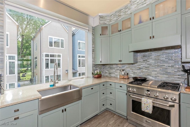 1569 E 118th St Unit B, Cleveland, OH 44106 - kitchen featuring high end range, under cabinet range hood, light wood finished floors, backsplash, and glass insert cabinets