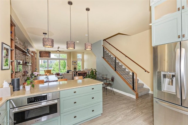 1569 E 118th St Unit B, Cleveland, OH 44106 - kitchen featuring appliances with stainless steel finishes, light wood finished floors, light countertops, and hanging light fixtures
