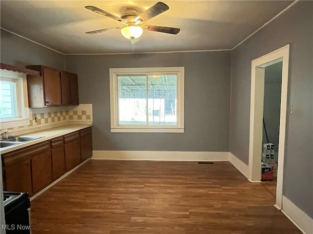907 Lovers Ln, Akron, OH 44306 - kitchen featuring dark wood-type flooring, ceiling fan, crown molding, decorative backsplash, and light countertops