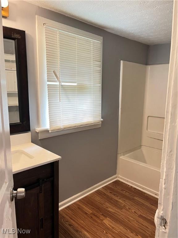 907 Lovers Ln, Akron, OH 44306 - bathroom with vanity, wood finished floors, a textured ceiling, and shower / tub combo