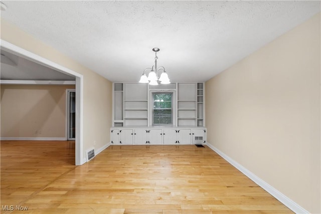 3965 Ellendale Rd, Chagrin Falls, OH 44022 - unfurnished dining area featuring a chandelier, light wood-style floors, built in features, and a textured ceiling