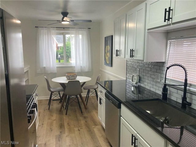 7611 Liberty Ave, Parma, OH 44129 - kitchen with appliances with stainless steel finishes, a ceiling fan, backsplash, dark countertops, and light wood-style floors