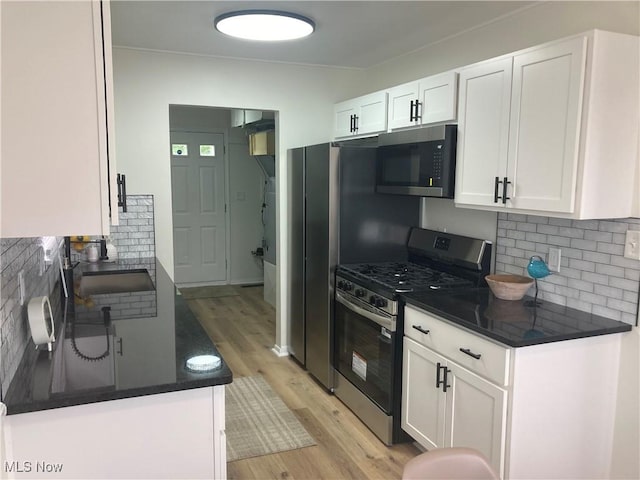 7611 Liberty Ave, Parma, OH 44129 - kitchen with stainless steel appliances, dark countertops, light wood finished floors, and backsplash