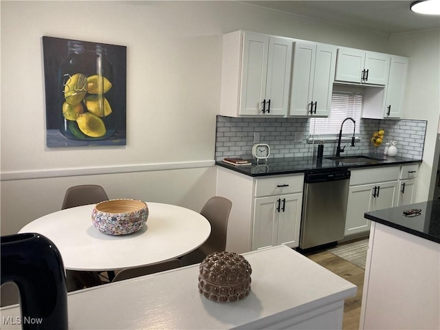 7611 Liberty Ave, Parma, OH 44129 - kitchen featuring stainless steel dishwasher, tasteful backsplash, white cabinetry, light wood finished floors, and dark countertops