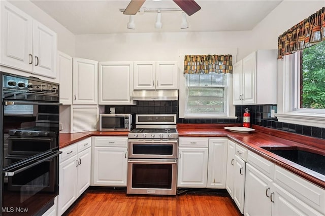 1575 E 108th St, Cleveland, OH 44106 - kitchen featuring stainless steel appliances, under cabinet range hood, dark countertops, a ceiling fan, and tasteful backsplash