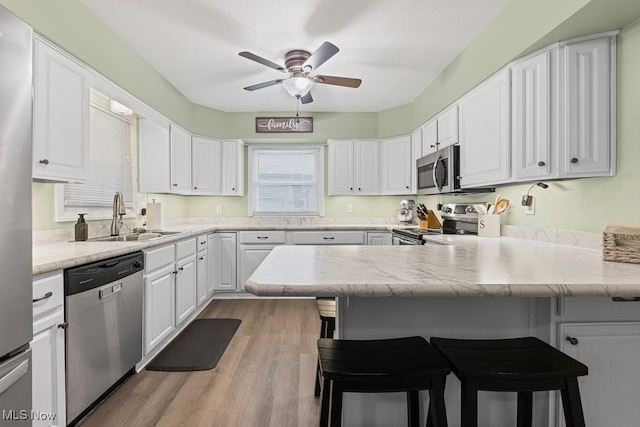 4000 Kenneth Rd, Stow, OH 44224 - kitchen featuring appliances with stainless steel finishes, white cabinets, ceiling fan, and a peninsula