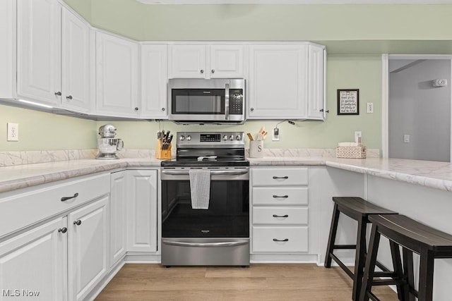 4000 Kenneth Rd, Stow, OH 44224 - kitchen with appliances with stainless steel finishes, white cabinets, light wood-type flooring, and light stone counters
