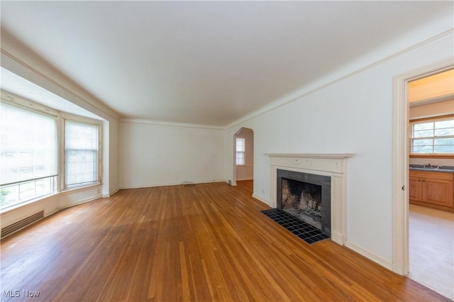 3526 Raymont Blvd, University Heights, OH 44118 - unfurnished living room with wood finished floors, a fireplace with flush hearth, and arched walkways