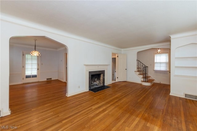 3526 Raymont Blvd, University Heights, OH 44118 - unfurnished living room featuring light wood-type flooring, a chandelier, arched walkways, stairs, and ornamental molding