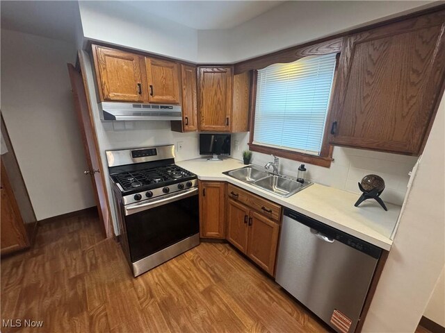 783 Jason Ave, Akron, OH 44314 - kitchen with appliances with stainless steel finishes, under cabinet range hood, wood finished floors, light countertops, and tasteful backsplash