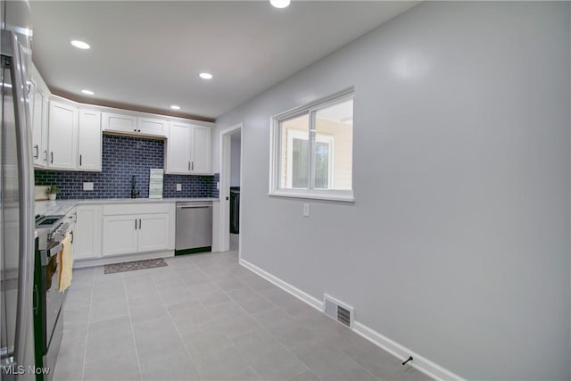 2764 Walter Rd, Westlake, OH 44145 - kitchen with dishwasher, decorative backsplash, stove, white cabinetry, and freestanding refrigerator