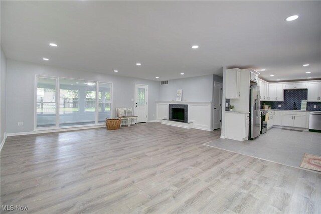 2764 Walter Rd, Westlake, OH 44145 - unfurnished living room with recessed lighting, a fireplace with raised hearth, and light wood finished floors