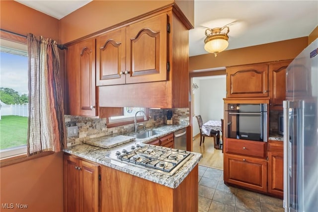 1455 Buckeye Cir, Salem, OH 44460 - kitchen featuring stainless steel appliances, brown cabinetry, decorative backsplash, a peninsula, and light stone countertops
