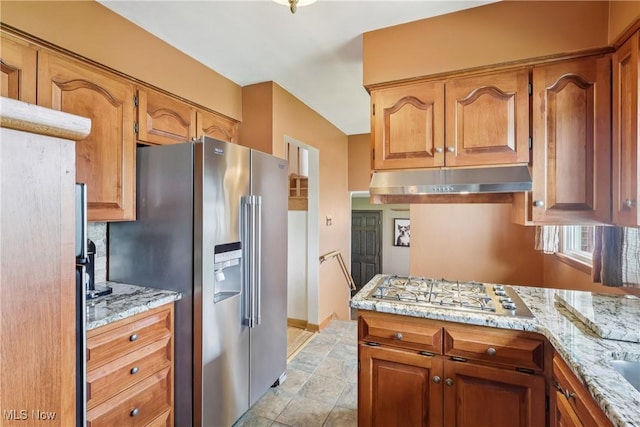 1455 Buckeye Cir, Salem, OH 44460 - kitchen with stainless steel fridge, under cabinet range hood, gas cooktop, light stone countertops, and brown cabinets