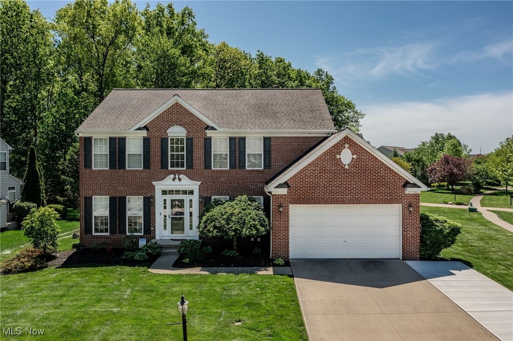 31500 Winners Cir, Avon Lake, OH 44012 - colonial inspired home featuring driveway, a garage, brick siding, a front lawn, and roof with shingles