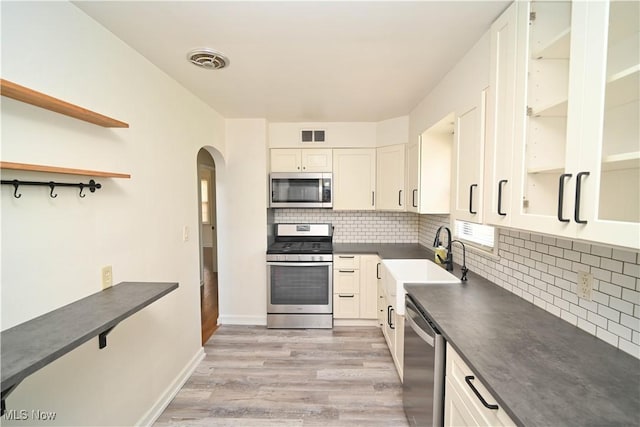 7673 N Lima Rd, Poland, OH 44514 - kitchen with appliances with stainless steel finishes, dark countertops, arched walkways, light wood-style flooring, and backsplash