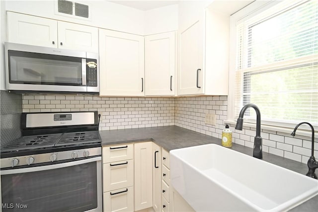 7673 N Lima Rd, Poland, OH 44514 - kitchen with appliances with stainless steel finishes, dark countertops, backsplash, and white cabinetry