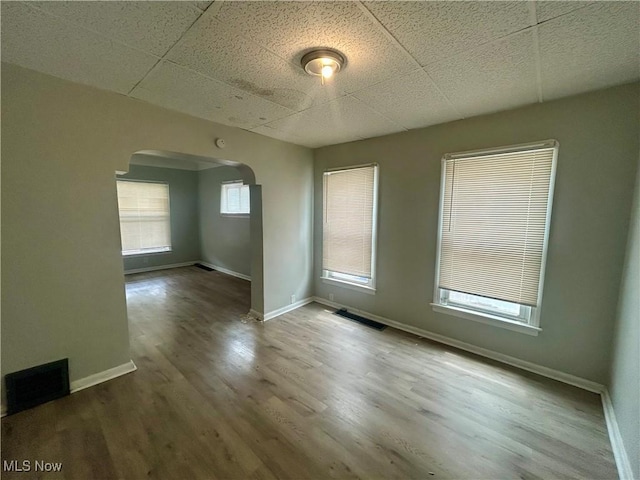 3180 W 90th St, Cleveland, OH 44102 - empty room with arched walkways, wood finished floors, and a drop ceiling