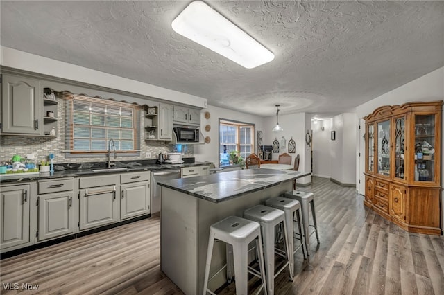 5065 Broadway, Lorain, OH 44052 - kitchen with open shelves, dishwasher, black microwave, a breakfast bar area, and decorative backsplash