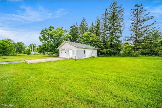 1518 State Route 46 N, Jefferson, OH 44047 - view of green lawn featuring concrete driveway, a garage, an outdoor structure, and view of wooded area