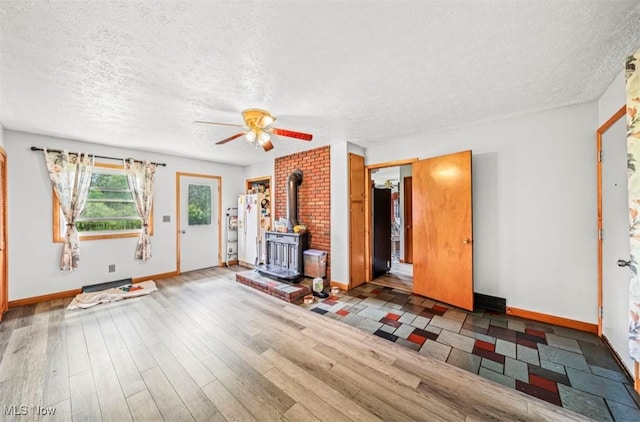 1518 State Route 46 N, Jefferson, OH 44047 - unfurnished living room featuring a wood stove, a textured ceiling, a ceiling fan, and wood finished floors