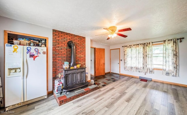 1518 State Route 46 N, Jefferson, OH 44047 - unfurnished living room with a textured ceiling, a wood stove, wood finished floors, and a ceiling fan
