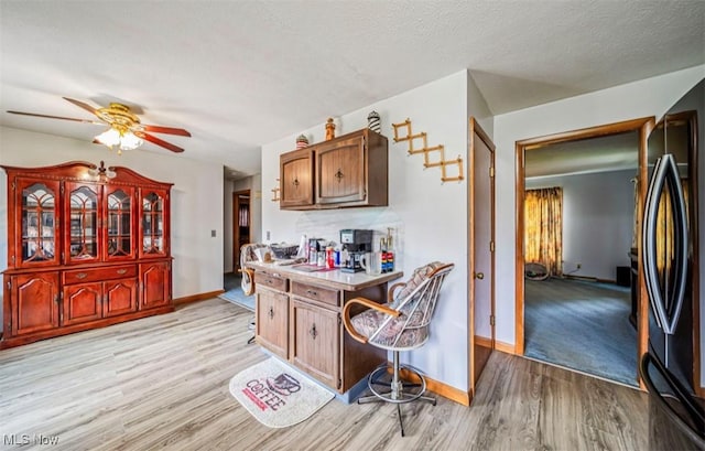 1518 State Route 46 N, Jefferson, OH 44047 - kitchen with black fridge, light wood-style floors, a ceiling fan, light countertops, and a textured ceiling