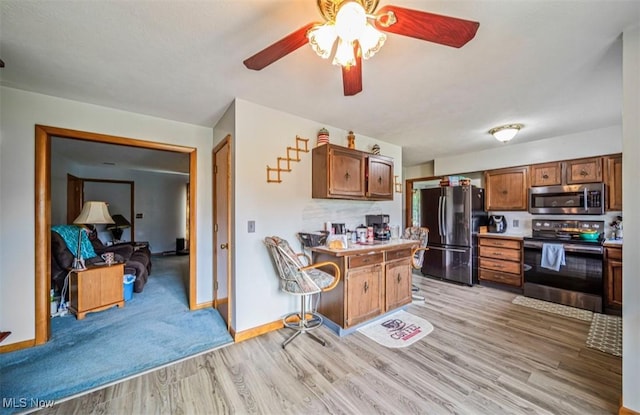 1518 State Route 46 N, Jefferson, OH 44047 - kitchen featuring stainless steel appliances, light wood-style flooring, a ceiling fan, light countertops, and brown cabinetry