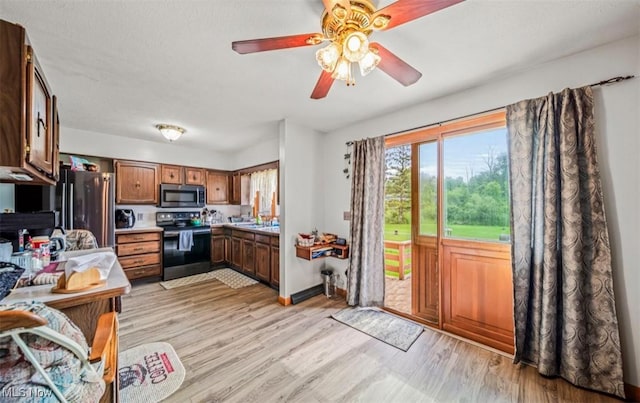 1518 State Route 46 N, Jefferson, OH 44047 - kitchen with stainless steel appliances, light wood-style flooring, a ceiling fan, light countertops, and brown cabinetry
