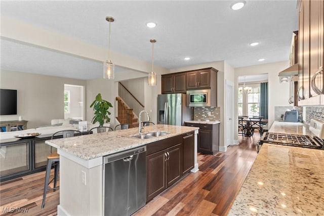 7733 Timber Ave, Hudson, OH 44236 - kitchen with appliances with stainless steel finishes, a kitchen bar, an island with sink, backsplash, and light stone countertops