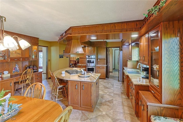 2307 Deerpath Dr, Sandusky, OH 44870 - kitchen featuring wood walls, appliances with stainless steel finishes, a kitchen island, brown cabinetry, and a textured ceiling