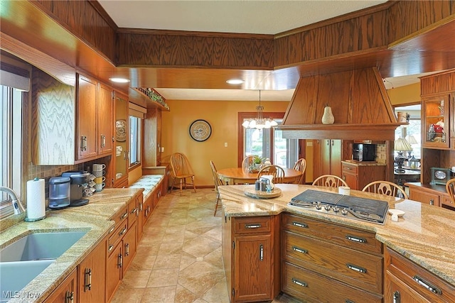 2307 Deerpath Dr, Sandusky, OH 44870 - kitchen with stainless steel gas cooktop, brown cabinets, decorative light fixtures, light stone countertops, and a chandelier