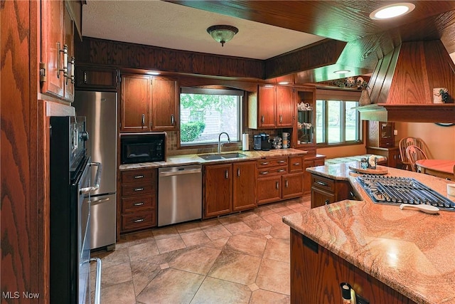 2307 Deerpath Dr, Sandusky, OH 44870 - kitchen featuring appliances with stainless steel finishes, brown cabinets, light stone countertops, and light tile patterned floors