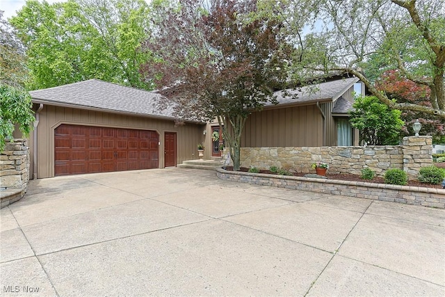2307 Deerpath Dr, Sandusky, OH 44870 - view of front of house with an attached garage, stone siding, concrete driveway, and a shingled roof