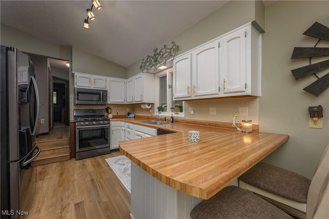 2436 Woodlawn Dr NW, Dover, OH 44622 - kitchen featuring appliances with stainless steel finishes, a peninsula, light wood-type flooring, white cabinets, and lofted ceiling