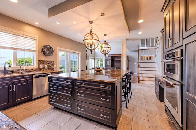 854 Crosstree Ln, Sandusky, OH 44870 - kitchen with appliances with stainless steel finishes, a chandelier, a breakfast bar area, dark stone counters, and recessed lighting