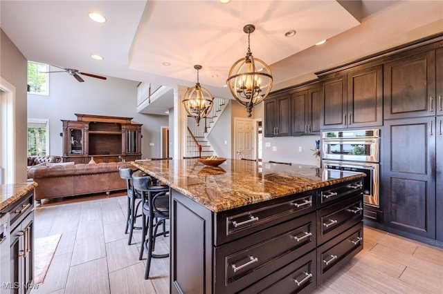 854 Crosstree Ln, Sandusky, OH 44870 - kitchen featuring double oven, a kitchen breakfast bar, stone countertops, a chandelier, and ceiling fan