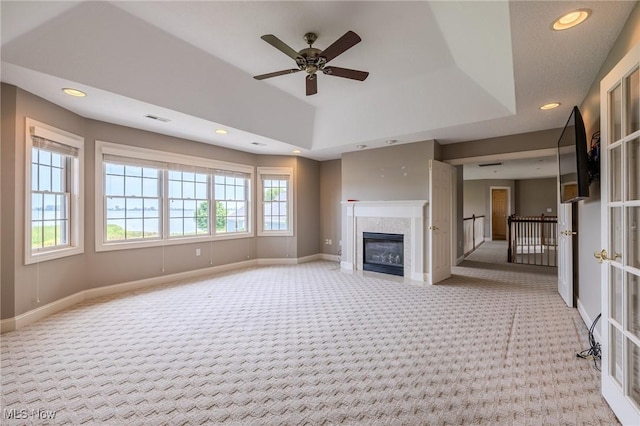 854 Crosstree Ln, Sandusky, OH 44870 - unfurnished living room featuring light colored carpet, recessed lighting, ceiling fan, a glass covered fireplace, and a tray ceiling