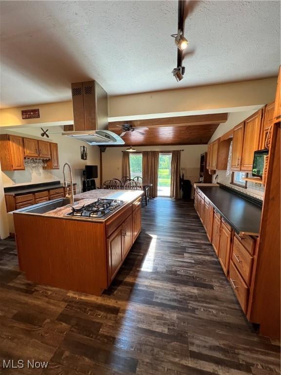 3290 NW Sweitzer St NW, Uniontown, OH 44685 - kitchen featuring stainless steel gas stovetop, island exhaust hood, dark wood-style flooring, dark countertops, and a textured ceiling