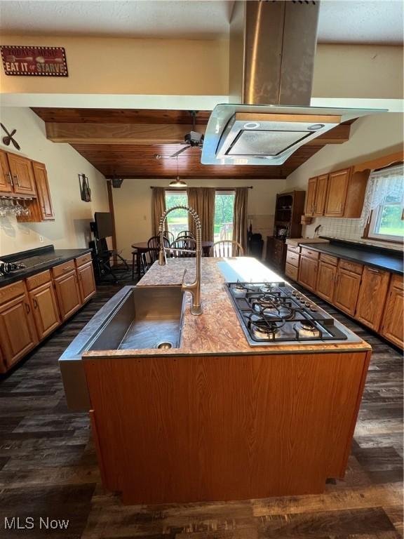 3290 NW Sweitzer St NW, Uniontown, OH 44685 - kitchen with island range hood, stainless steel gas stovetop, dark wood-style flooring, an island with sink, and beamed ceiling