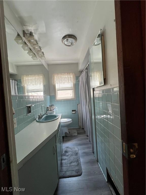 3290 NW Sweitzer St NW, Uniontown, OH 44685 - full bathroom featuring tile walls, vanity, a shower with shower curtain, wainscoting, and wood finished floors