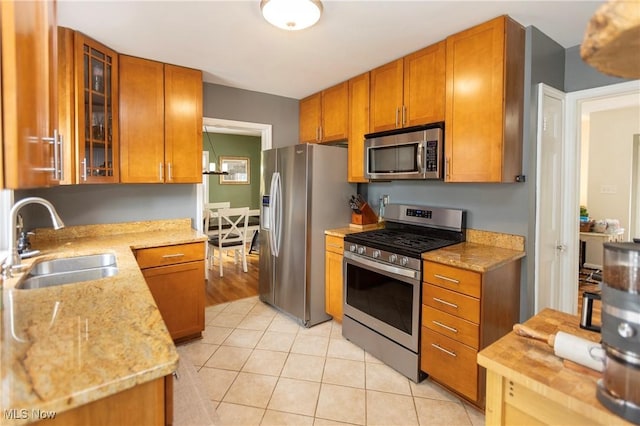 3678 Lynnfield Rd, Shaker Heights, OH 44122 - kitchen with appliances with stainless steel finishes, light tile patterned floors, brown cabinetry, and glass insert cabinets